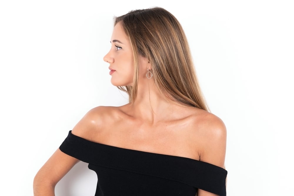 Smiling woman shows her side profile after a rhinoplasty procedure